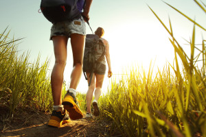 Hikers with backpacks walking through a meadow with lush grass